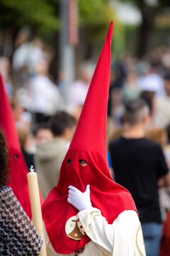 Nazareno, bearer in a procession of the easter week in Seville, andalusia, Spain. 2024 Semana Santa. Red hood, procession of 23.03.2024