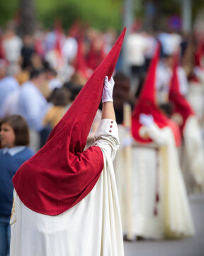 Nazareno, bearer in a procession of the easter week in Seville, andalusia, Spain. 2024 Semana Santa. Red hood, procession of 23.03.2024