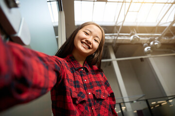 High angle view of young smiling asian female IT employee looking at camera
