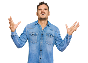 Young hispanic man wearing casual denim jacket crazy and mad shouting and yelling with aggressive expression and arms raised. frustration concept.
