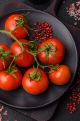 Fresh red cherry tomatoes on a branch on a dark concrete background