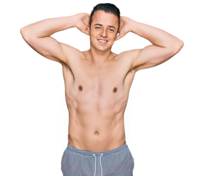 Handsome young man wearing swimwear shirtless relaxing and stretching, arms and hands behind head and neck smiling happy