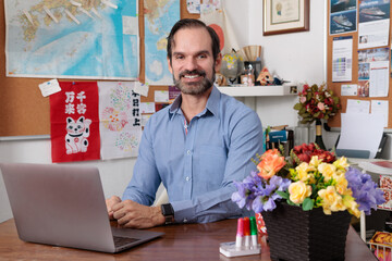 Experimentado profesor adulto latino dando clases de japonés en línea en su estudio casero,...