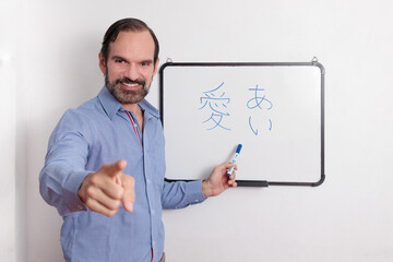 Profesor adulto latino dando clases de japonés en pequeña pizarra acrílica. Señalando a los...