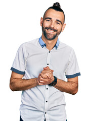 Hispanic man with ponytail wearing casual white shirt with hands together and crossed fingers...