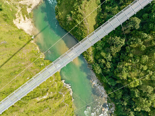 Aerial view of a Tibetan suspended bridge in Nepal is a primitive type of bridge in which the deck...