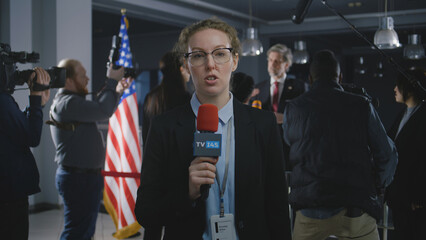 Caucasian anchorwoman reports breaking news live from government building. Female journalist leads...