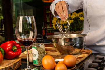 Chef prepara receita com ingredientes frescos, colocando farinha na tigela tomando vinho em cozinha...