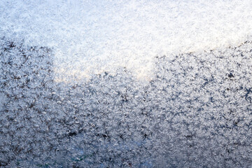 frosty pattern on window glass of residential apartment close up and silhouette of city buildings...