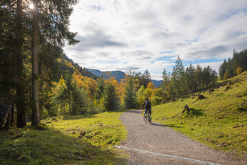 biker at oytal route near Oberstdorf, autumnal forest and grey clouds, tourist resort allgau