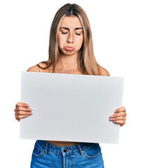 Hispanic young woman holding blank empty banner depressed and worry for distress, crying angry and afraid. sad expression.