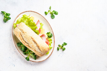 Fast food sandwich with lettuce, cheese, tomatoes and ham. Flat lay on white table.