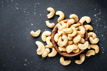 Cashew nuts in bowl at black background. Flat lay with space for text.