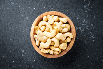 Cashew nuts in bowl at black background. Flat lay with space for text.