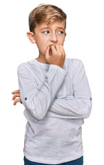 Little caucasian boy kid wearing casual clothes looking stressed and nervous with hands on mouth...
