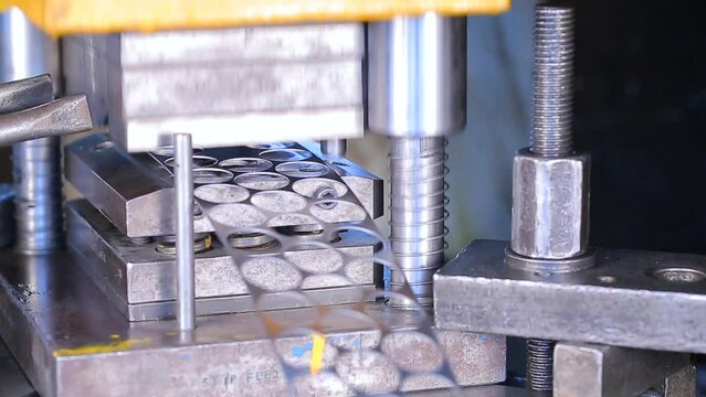 automatic machine punching holes circles in metal aluminum sheets. Close up shot of a punch press forming circular hole metal parts to manufacture tools in production line. Industrial Machine. factory