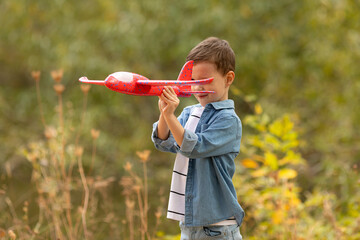 Child pilot aviator with airplane dreams of traveling in summer in nature at sunset