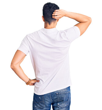 Young handsome hispanic man wearing casual clothes backwards thinking about doubt with hand on head