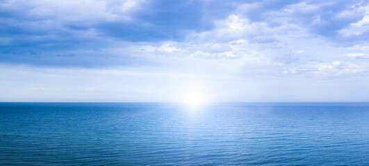 Calm windless ocean with the sun on the horizon.