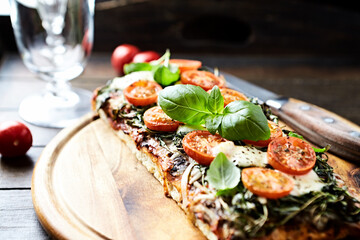 Open-faced toasted cheese sandwich with cherry tomatoes, spinach and fresh basil. Brown wooden background.	