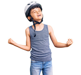 Little cute boy kid wearing bike helmet very happy and excited doing winner gesture with arms raised, smiling and screaming for success. celebration concept.