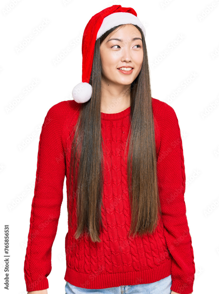 Wall mural Young chinese woman wearing christmas hat looking away to side with smile on face, natural expression. laughing confident.