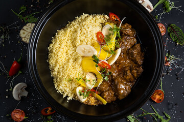 Traditional tajine dishes, couscous and fresh salad on rustic wooden table. Tagine lamb meat and...