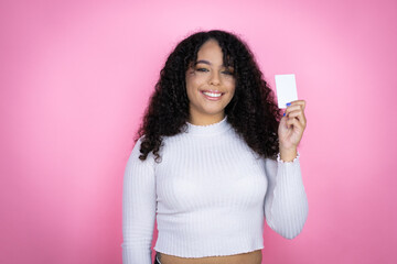 African american woman wearing casual sweater over pink background smiling and holding white card