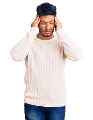 Naklejka premium Handsome latin american young man wearing casual winter sweater suffering from headache desperate and stressed because pain and migraine. hands on head.