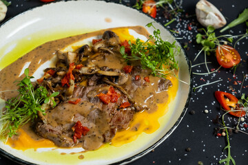Tender veal with mushrooms is served in deep dish, filled with thick fragrant gravy. Tender meat is garnished with stewed vegetables and herbs.