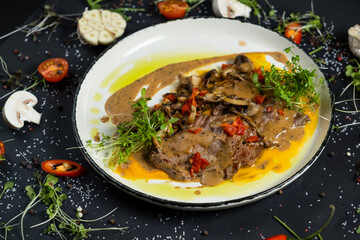 Tender veal with mushrooms is served in deep dish, filled with thick fragrant gravy. Tender meat is garnished with stewed vegetables and herbs.