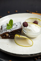 Brownie in plate with ice cream on black background