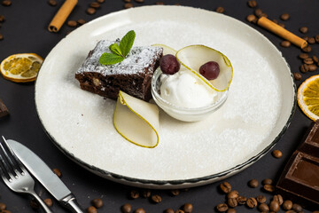 Brownie in plate with ice cream on black background
