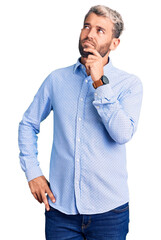 Young handsome blond man wearing elegant shirt with hand on chin thinking about question, pensive expression. smiling with thoughtful face. doubt concept.