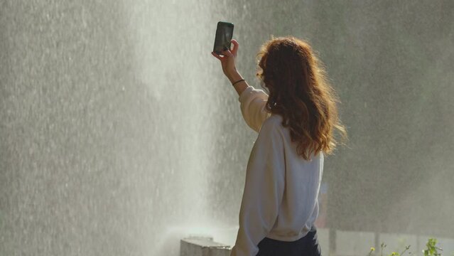 Female taking picture for blog nature waterfall background