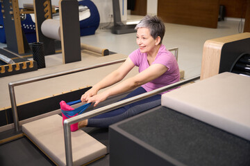 Woman stretching with resistance band after injury in rehabilitation gym