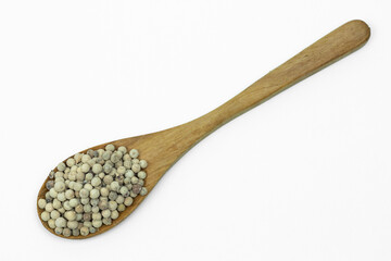 Close up of Dried white pepper seeds on wooden spoon isolated on white background