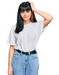 Fototapeta premium Young hispanic girl wearing casual clothes confuse and wonder about question. uncertain with doubt, thinking with hand on head. pensive concept.
