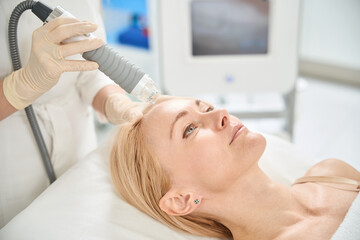 Obraz na płótnie Canvas Cosmetologist making microneedle RF-lifting procedure for woman