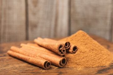 Cinnamon sticks on a textured wooden background. Cinnamon roll. Spicy spice for baking, desserts and drinks. Fragrant ground cinnamon. cinnamon powder Close-up. Place for text. copy space