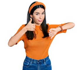 Young hispanic woman wearing casual clothes doing thumbs up and down, disagreement and agreement expression. crazy conflict