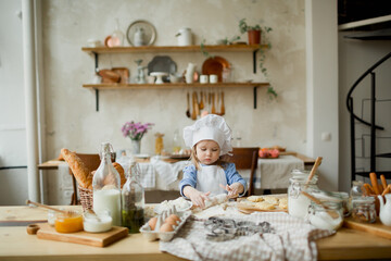 Girl cook 3 years old in a beautiful kitchen, in a chef's hat, in an apron, daylight