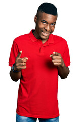 Young african american man wearing casual red t shirt pointing fingers to camera with happy and funny face. good energy and vibes.