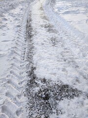 Tractor tracks in the snow. A pedestrian road with a tire pattern.