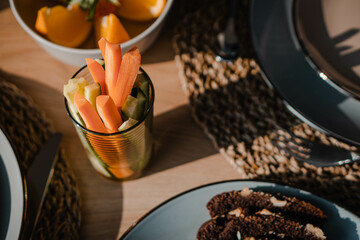 Starting the Day Fresh: Enjoying a Vegan Breakfast with Colorful Vegetable Sticks of Carrots and Cucumbers, Enhanced by Decorations under the Morning Sun