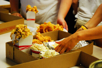 Workers at a seafood restaurant quickly prepare and package a meal during a busy night