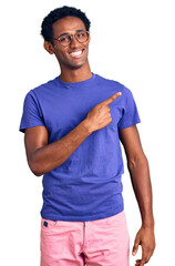 Fototapeta premium African handsome man wearing casual clothes and glasses cheerful with a smile of face pointing with hand and finger up to the side with happy and natural expression on face