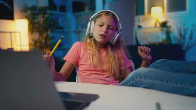 Funny young girl in headset enjoying music instead of studying, moving to rhythm