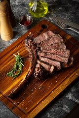 sliced tomahawk steak on wooden board