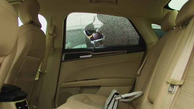 Criminal car thief smashes break car window snatches bag from back seat. Carjacker break window glass seizes opportunity swiftly grabbing stolen belongings Car thief break car window glasses.